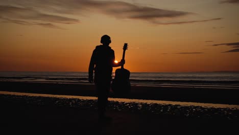 Man-running-with-guitar-in-back-sand-beach-at-sunset-16