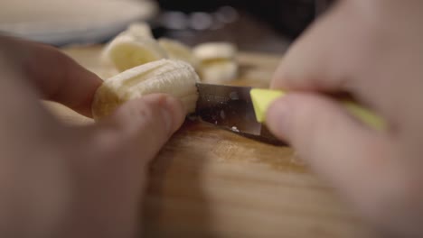 Close-up-Of-Woman-Cutting-A-Delicious-Banana-On-A-Wooden-Chopping-Board