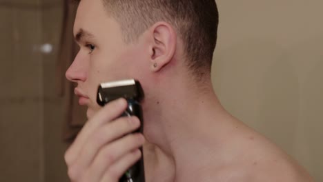 A-young-person-trims-their-face-with-an-electric-shaver