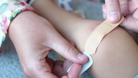 Close-Up-Mother's-Hand-putting-Adhesive-Bandage-on-Child's-Knee-Wound