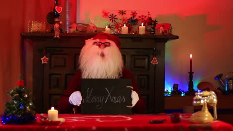 Santa-Claus-Showing-Merry-Xmas-Note-On-Chalk-Blackboard