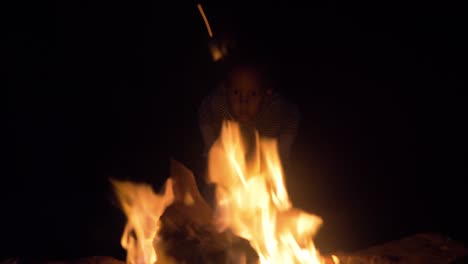 A-young-mixed-raced-child's-face-is-lit-up-by-the-light-of-a-camp-fire-at-night