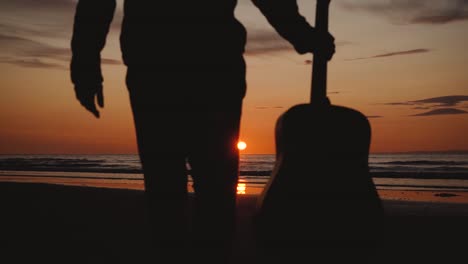 Man-running-with-guitar-in-back-sand-beach-at-sunset-2
