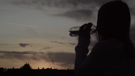 Allein-Frau-Silhouette-Trinkflasche-Wasser-Bei-Sonnenuntergang