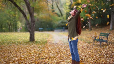 Slow-Motion:-Beautiful-young-redhead-woman-standing-in-a-park-in-autumn-with-leaves-falling-down-around-her-2