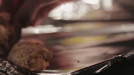 A-Woman-Carefully-Putting-Breaded-Meat-In-A-Mettalic-Tray-With-Foil---Close-Up-Shot