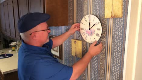 Hombre-Ajustando-El-Reloj-Por-Tiempo-En-La-Pared-De-La-Cocina