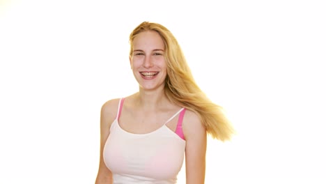 A-wind-machine-blows-a-woman's-long-blonde-hair-as-she-poses-and-giggles-against-a-plain-white-studio-background