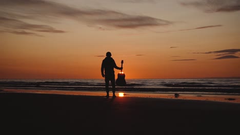 Man-running-with-guitar-in-back-sand-beach-at-sunset-17