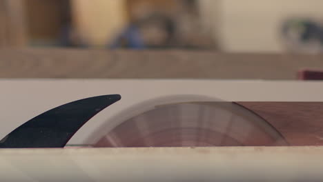 A-wood-board-is-shaved-on-a-table-saw,-close-up-side-view-in-slow-motion