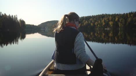 Woman-paddling-canoe-boat-on-beautiful-lake-in-autumn,-rear-view-slow-motion-1