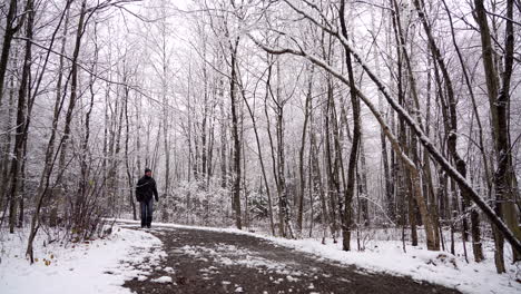 Man-walking-on-a-trail-with-snow