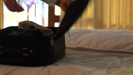 Man-hands-preparing-suitcase-on-bed.-Static-shot