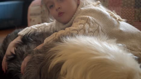 Girl-affectionately-lays-on-back-of-Australian-Shepherd-dog-at-home