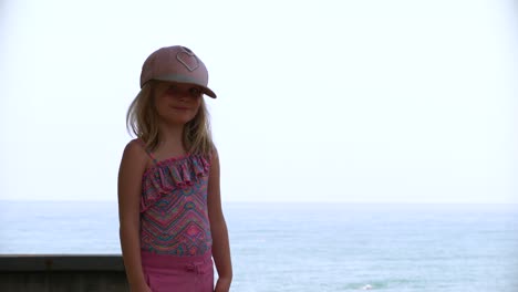 Portrait-of-blonde-child-girl-with-sun-hat-and-sea-in-background