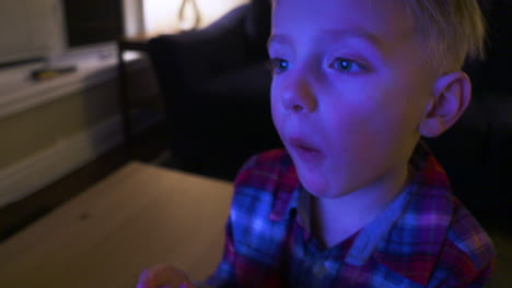 Close-up-of-a-little-boy's-face-as-he-watches-TV-and-eats-popcorn