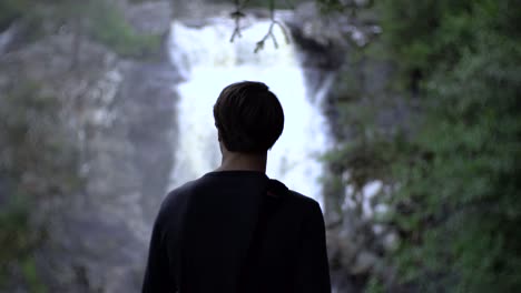 Mann-Steht-Vor-Wasserfall,-Schöne-Und-Erstaunliche-Aussicht-Während-Der-Wanderung