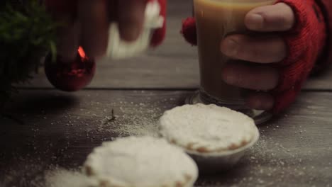 Hand-Mit-Winterhandschuhen,-Die-Kuchen-Und-Kaffee-Im-Weihnachtshintergrund-Greifen