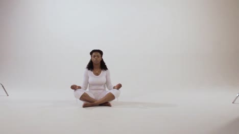 Young-Black-yogi-moving-between-meditation-poses,-easy-pose-to-prayer-pose