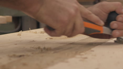 Low-angle-slow-motion-close-up-of-a-carpenter-using-a-planer-on-wood-boards-in-his-shop