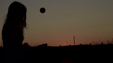 Frau-In-Der-Silhouette-Der-Einsamkeit,-Die-Bei-Sonnenuntergang-Einen-Ball-In-Die-Luft-Wirft-1