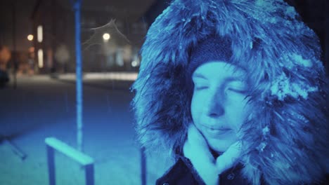 Junge-Frau-Mit-Schneebedeckter-Pelzkapuze-Steht-Nachts-Im-Blauen-Licht-In-Einer-Winterlichen-Landschaft