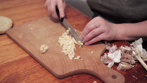 Woman's-hands-with-a-knife-chops-garlic-on-a-chopping-board