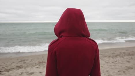 A-Person-Wearing-A-Red-Hoodie-Jacket-Watching-The-Ocean-Waves---Close-Up-Shot