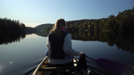 Woman-paddling-canoe-boat-on-beautiful-autumn-lake,-rear-view-1