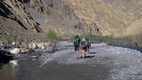 A-group-of-hikers-walking-in-a-dried-out-river-bed-in-the-mountains