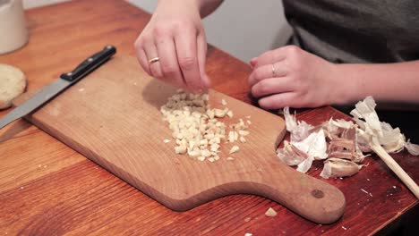 Woman's-hands-salt-garlic-and-crushes-with-a-knife-on-a-chopping-board