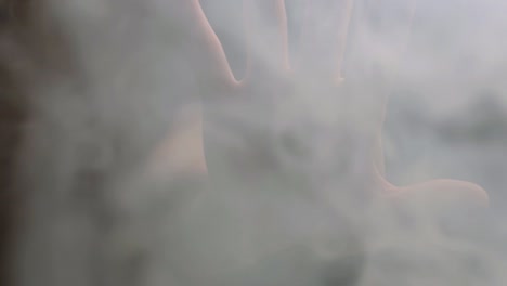 Ausgestreckte-Hand-In-Rauchgasen-Vor-Dunklem-Hintergrund