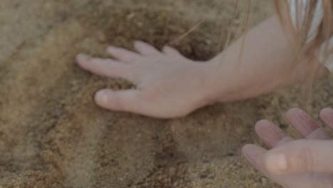 Frauenhand-Genießt-Das-Spielen-Mit-Sand