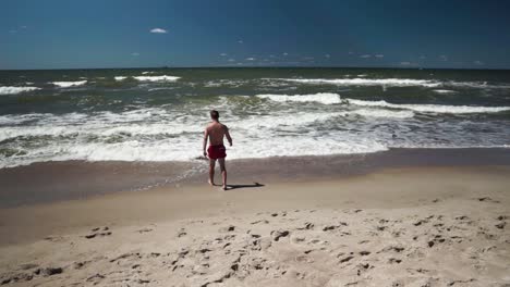 Young-man-in-red-shorts-goes-to-sea-in-a-beach-1