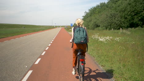 Female-cyclist-with-backpack-no-helmet-riding-slow-motion-along-a-path