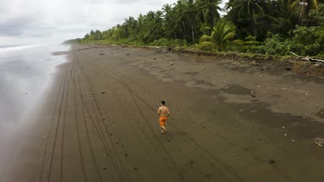 Aerial-shot-of-a-guy-jogging-at-an-empty-beach-in-Colombia-1