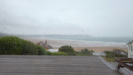 Static-Shot-of-Raindrops-Falling-Down-a-Window-with-an-Ocean-View-in-Slow-Motion