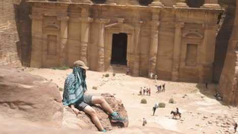 Hombre-Aventurero-Sentado-En-Una-Roca,-Tiro-Estático,-Petra-Jordan,-Templo-De-Fondo