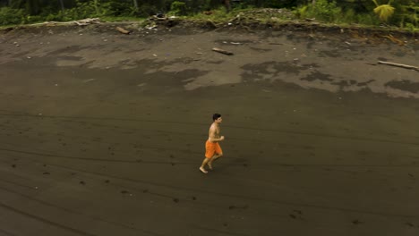Aerial-shot-of-a-guy-jogging-at-an-empty-Beach-in-Colombia