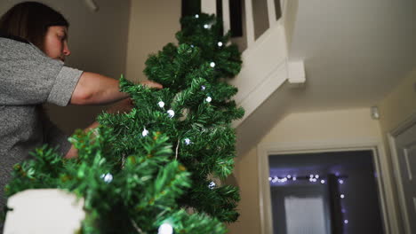 Woman-decorating-her-home-with-lighted-garland-for-the-Christmas-season