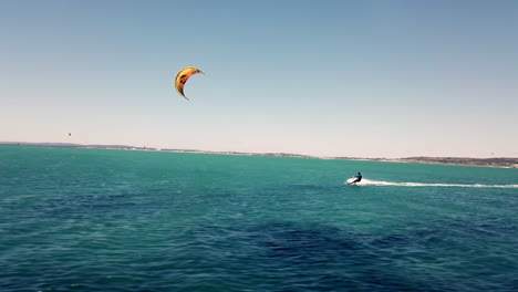 Speed-drone-fly-by-wide-shot-chasing-a-kite-surfer-on-full-speed-in-beautiful-natural-daylight-sun-with-blue-sky-on-Langebaan-Beach,-Cape-Town,-South-Africa-with-summer-vacation-silhouette