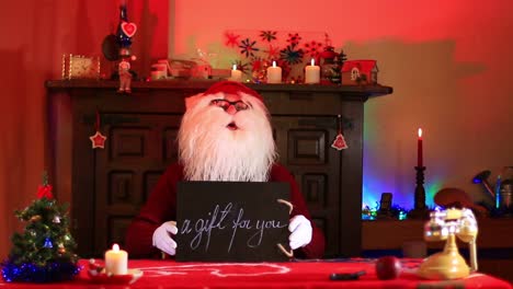 Santa-Claus-Showing-A-Gift-For-You-Note-On-Black-Chalkboard