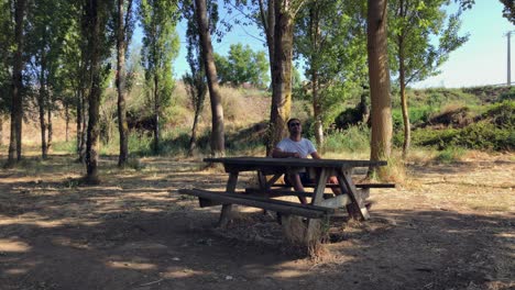 Man-sitting-at-a-wooden-table-in-the-forest-1