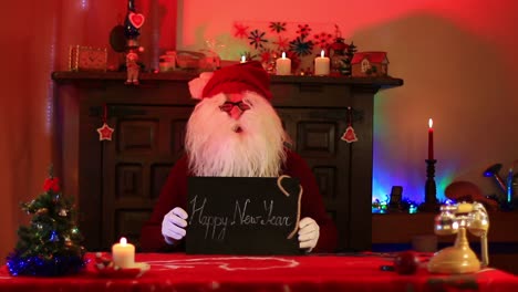 Santa-Claus-Showing-Happy-New-Year-Note-On-Chalk-Blackboard