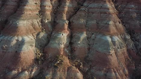 Male-Standing-on-Sandstone-Rock-Formation-Cliff-in-Utah-Desert,-Aerial-View