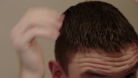 Close-up-of-a-young-person-applying-gel-to-short-hair