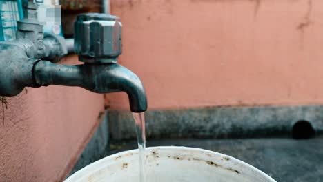 A-flowing-tap-with-background-showing-old-wall-in-the-mid-day
