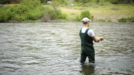 Slow-Motion-Shot-of-a-Caucasian-male-fisherman-casting-his-hook-while-Fly-Fishing-1