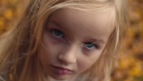 Young-girl-with-blond-hair-and-blue-eyes-stares-intensely-into-camera