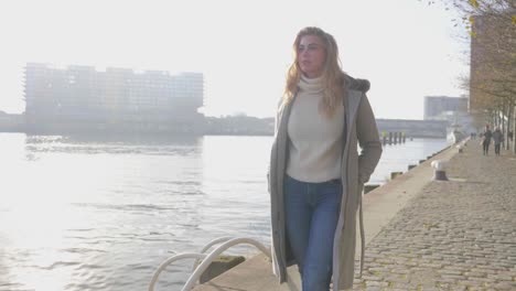Introspective-young-woman-walks-along-a-pier-in-slow-motion